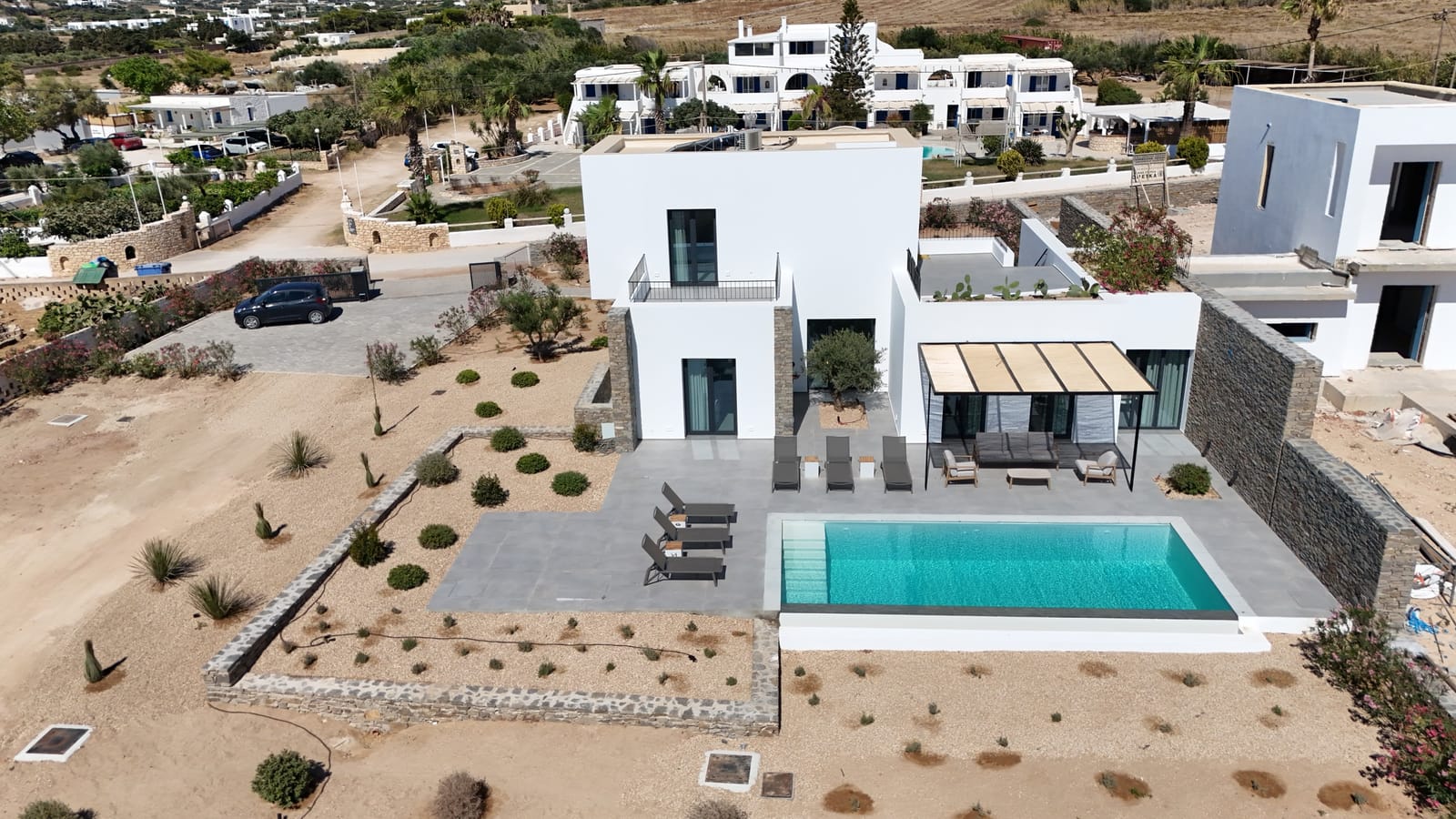 Aerial view of Villa Sabbia, a white cubic residence with overflow pool and stone terraces at Ampelas